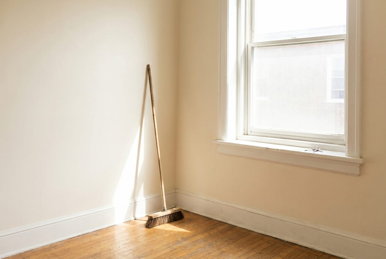Leergeräumtes, besenreines Zimmer mit Besen und Schlüsseln auf der Fensterbank